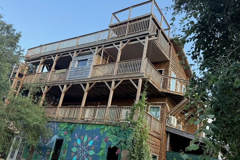 The four-story Heavenly View lodge with wraparound wooden decks on every level, behind a natural pond.