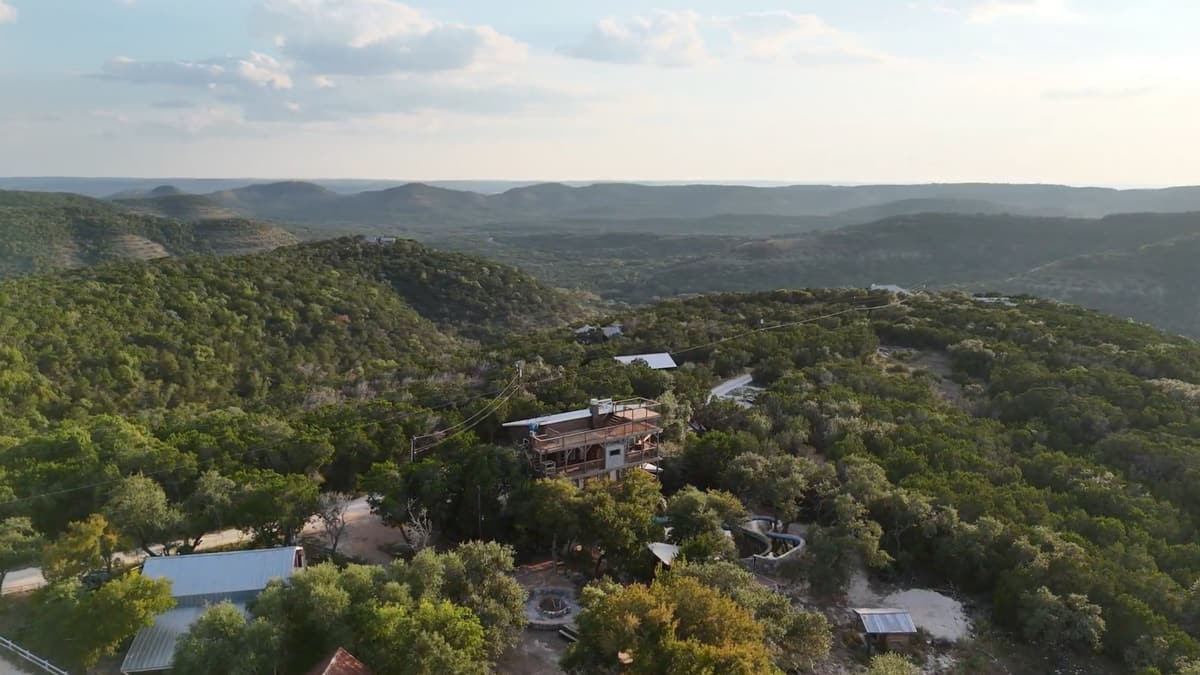 Aerial view of Heram Al Noor: the Heavenly View lodge among cedar and oak, with Hill Country ridges rolling to the horizon.