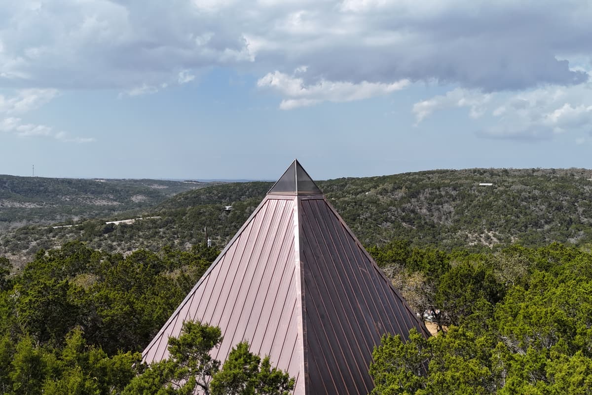 The copper-roofed pyramid rising above green cedar and oak, with rolling hills to the horizon.