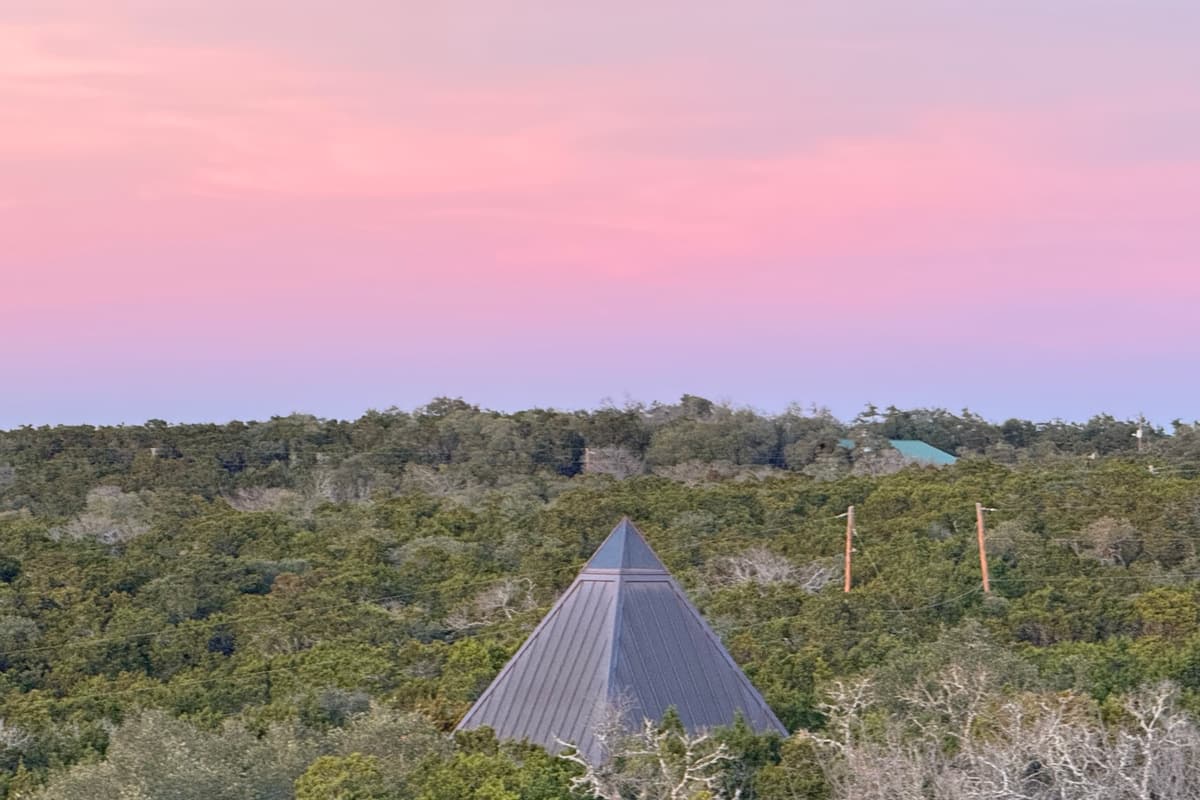 The pyramid among the trees under a soft pink dusk sky.