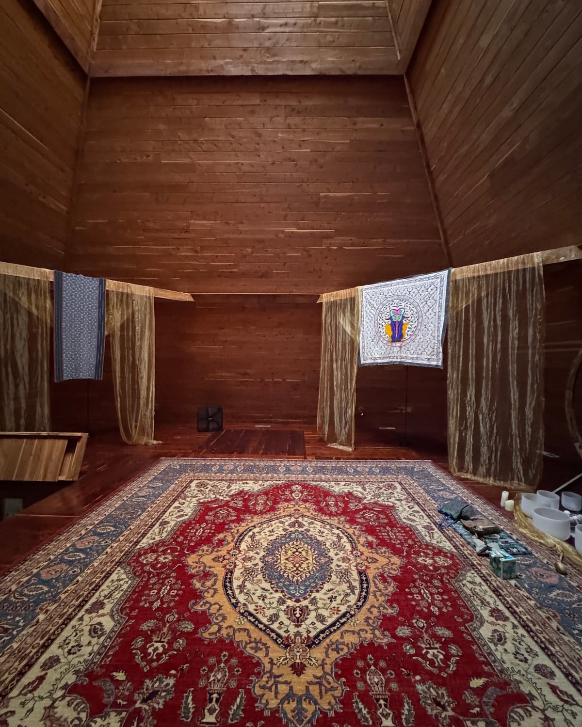 Inside the pyramid: warm cedar walls rising to a skylight above a large patterned rug.